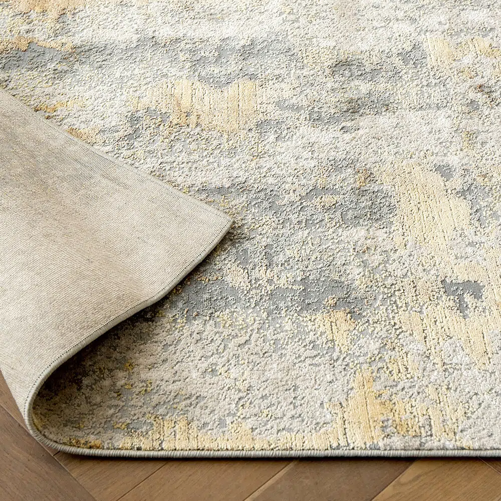 Close-up of the Aurora rug showcasing its backing and high-pile grey and gold abstract design.