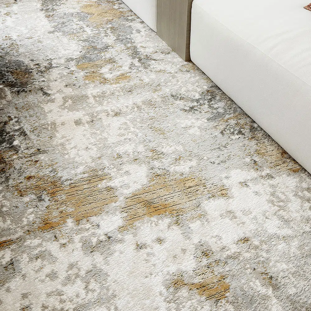 Detailed view of the Aurora rug with grey and gold tones, placed under a modern white sofa.