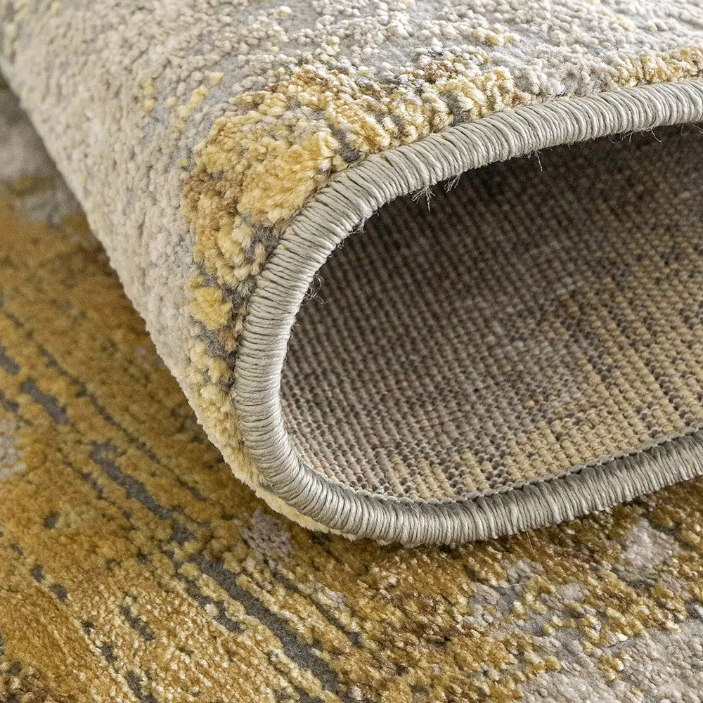 Close-up of the Aurora rug showcasing its high-pile texture, grey and gold abstract design, and durable stitching.