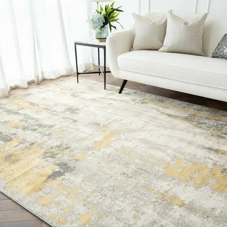 Aurora rug with grey and gold tones, styled in a bright living room with a white sofa and minimalist decor.