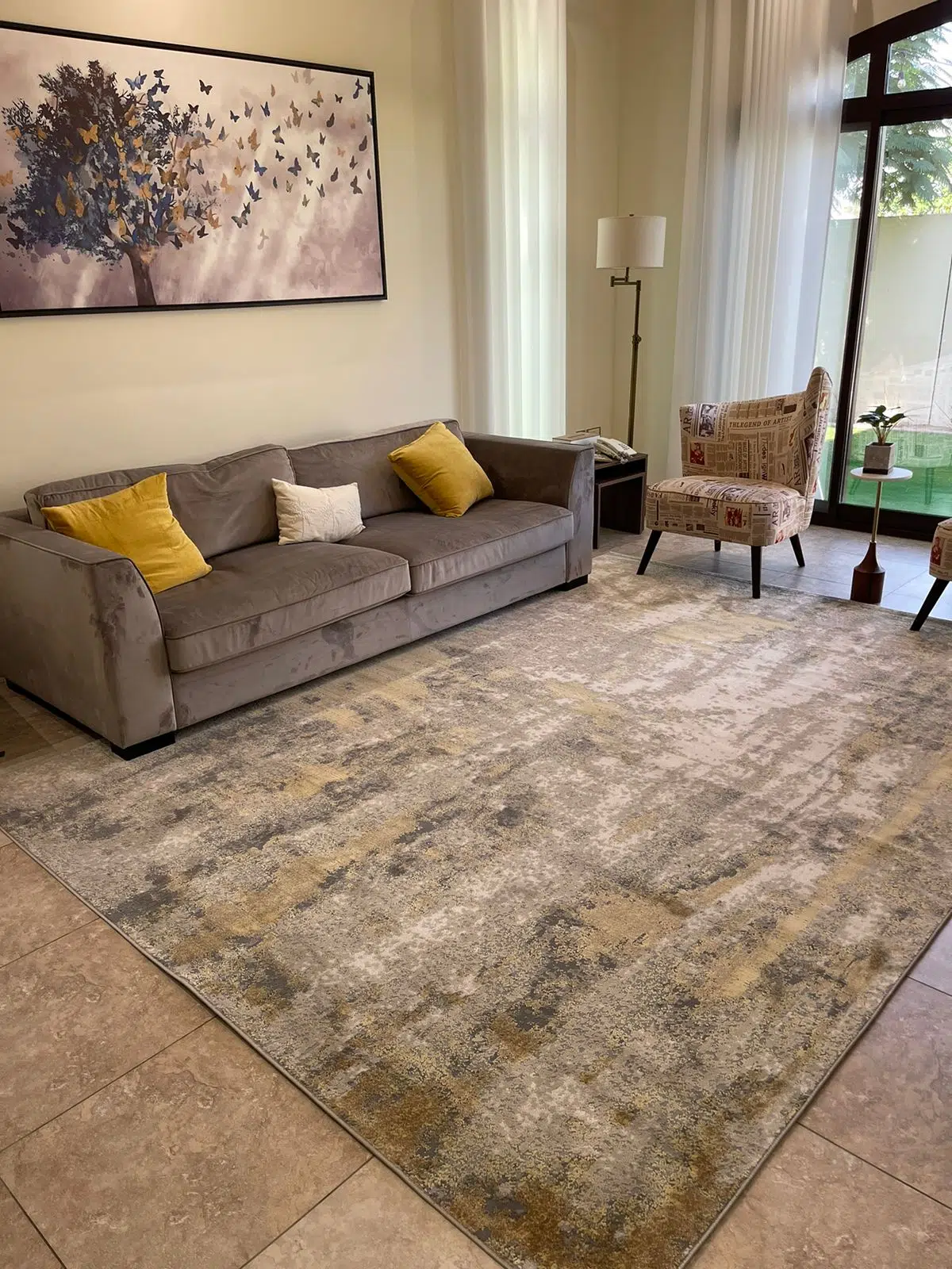 Aurora rug with grey and gold design, styled in a cozy living room with a grey sofa and artistic wall art.