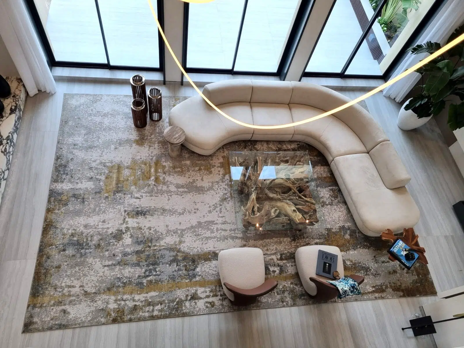 Aurora rug with grey and gold tones, styled in a modern open living space featuring a curved beige sofa and glass coffee table.