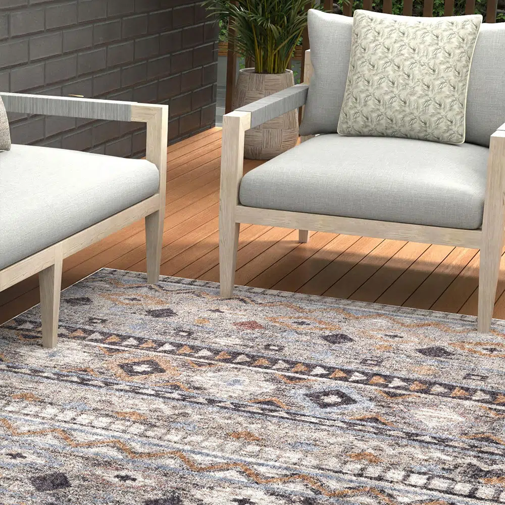 Boho Mirage Rug with geometric patterns and earthy tones, styled with modern outdoor furniture on a wooden patio.