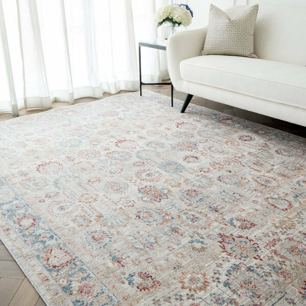 The Bustan Rug with intricate floral motifs and soft beige tones, styled in a bright living room with a white sofa and natural light.