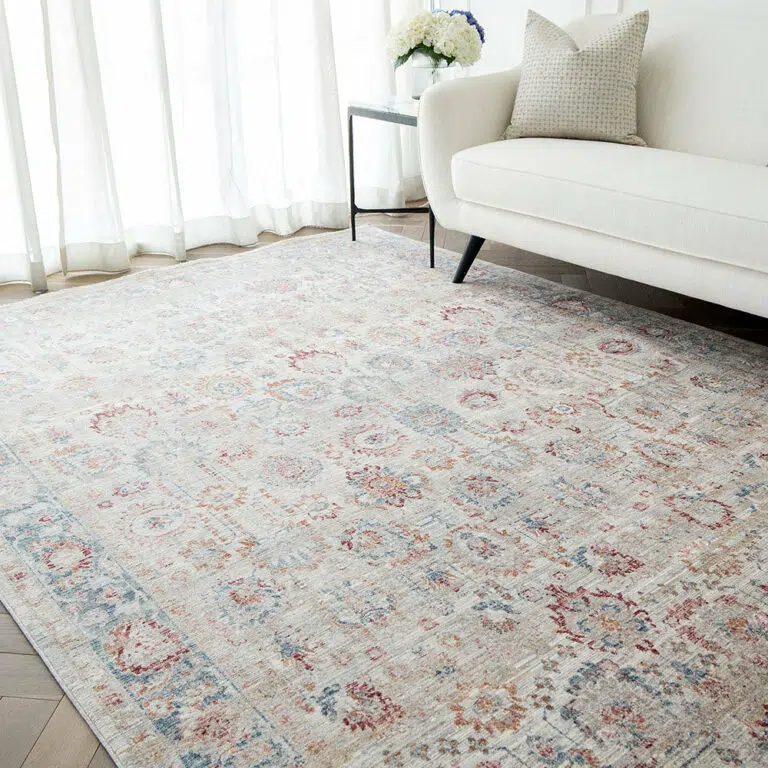 The Bustan Rug with intricate floral motifs and soft beige tones, styled in a bright living room with a white sofa and natural light.