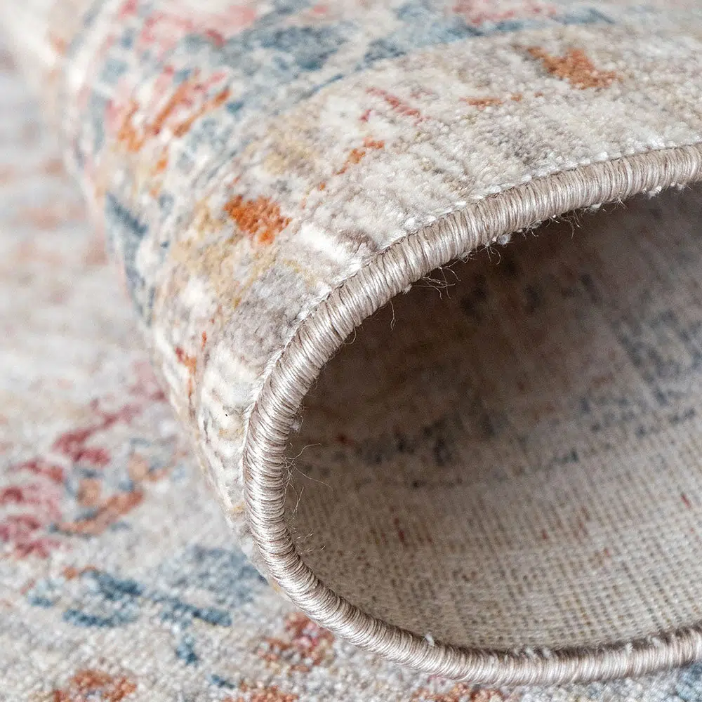 Detailed close-up of the Bustan Rug's durable edging and intricate floral patterns in beige, blue, and red tones.