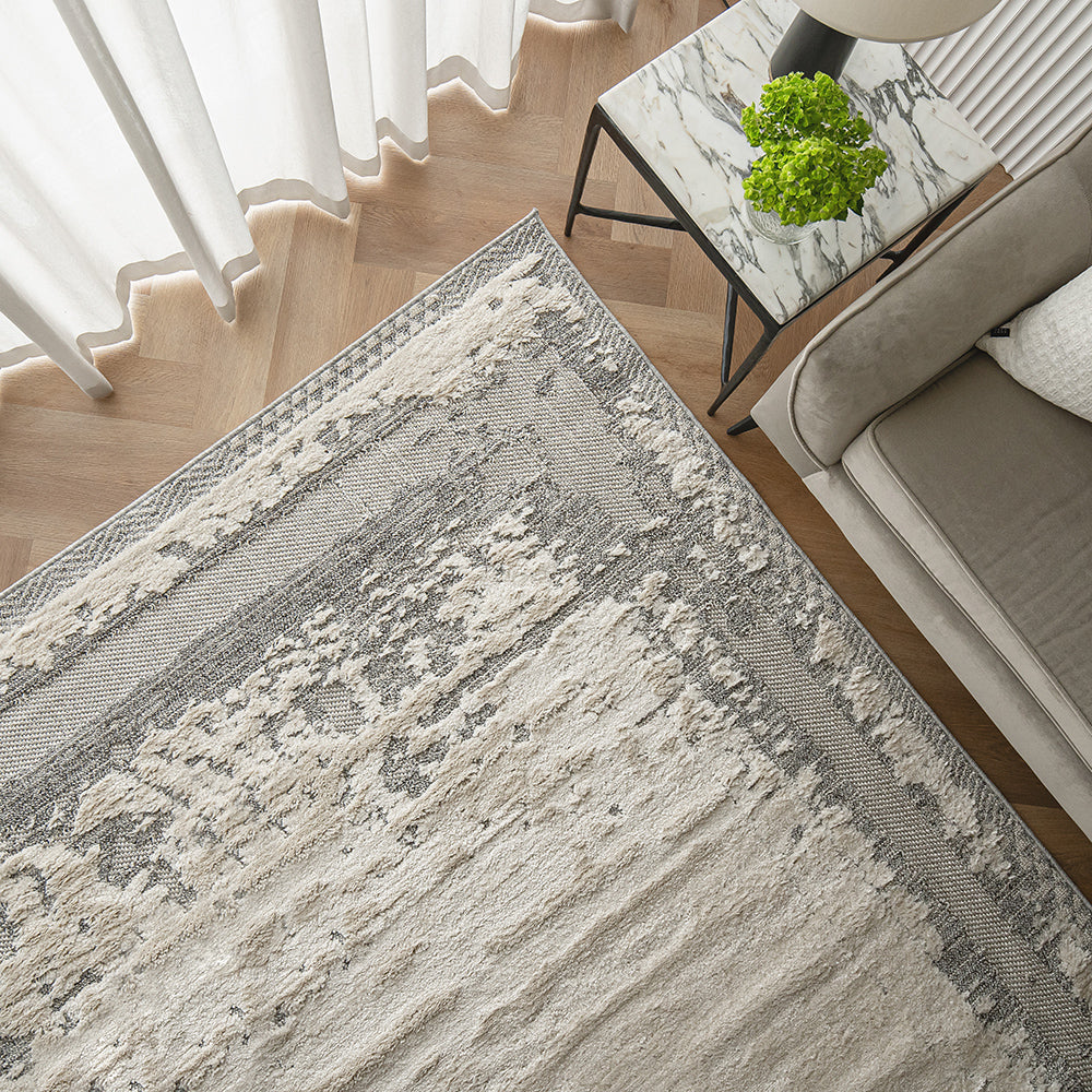 Top-down view of the Mist Haven Rug, showcasing its distressed gray and cream design, styled with modern furniture and marble decor.