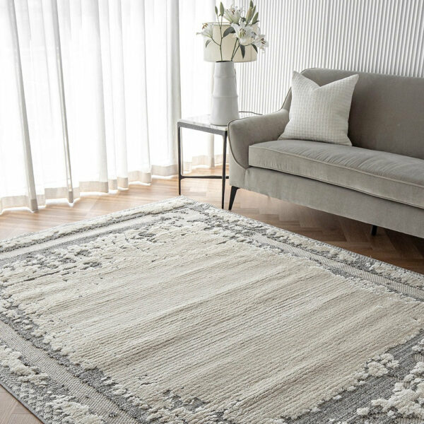 Mist Haven Rug styled in a bright living room with a gray sofa and white floral decor, featuring a distressed gray and cream design.