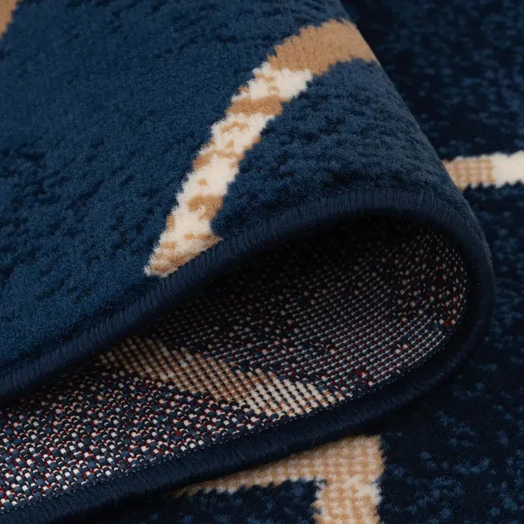 A close-up view of the Alhambra Geometric Rug in navy blue, highlighting its soft texture, precise weave, and detailed backing material.